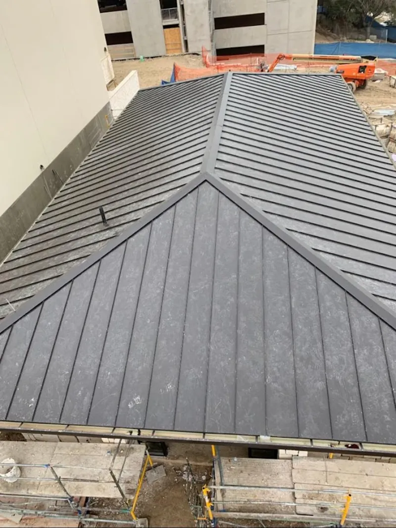 Commercial metal roof construction with crane equipment in East Riverdale